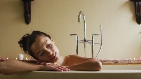 Portrait-of-relaxed-biracial-woman-lying-in-bath-and-thinking