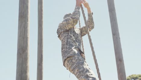 Soldado-Caucásico-En-Uniforme-Bajando-La-Cuerda-En-Una-Carrera-De-Obstáculos-Militares-Bajo-El-Sol