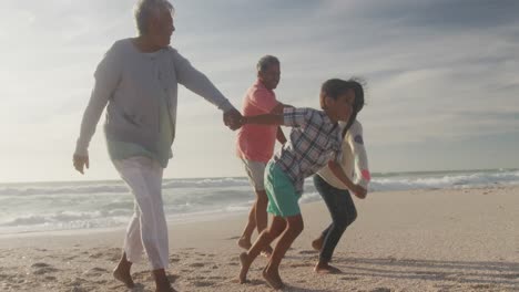 Glückliche-Hispanische-Großeltern-Und-Enkelkinder,-Die-Bei-Sonnenuntergang-Am-Strand-Laufen
