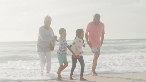Glückliche-Hispanische-Großeltern-Und-Enkelkinder,-Die-Bei-Sonnenuntergang-Am-Strand-Spazieren-Gehen