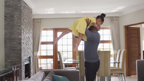 Happy-african-american-father-lifting-up-daughter-and-having-fun-in-living-room