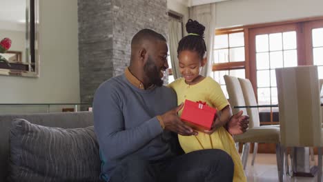 Happy-african-american-daughter-giving-present-to-surprised-father