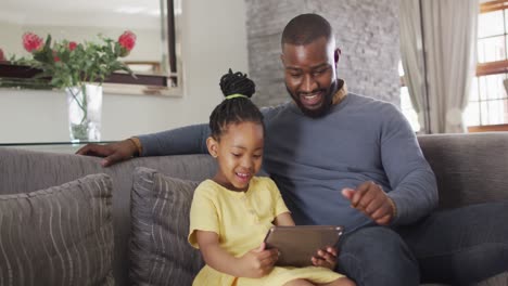 Feliz-Hija-Y-Padre-Afroamericano-Usando-Tableta-En-El-Sofá