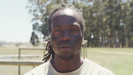 Portrait-of-confident-african-american-male-soldier-with-dreadlocks-and-eye-black-in-field