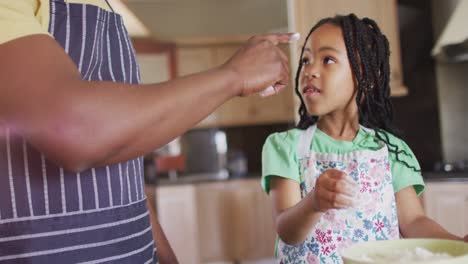 Happy-african-american-father-and-daughter-baking-together,-playing-with-flour-in-kitchen