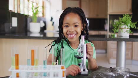 Feliz-Niña-Afroamericana-Usando-Microscopio,-Haciendo-Experimentos-En-Casa