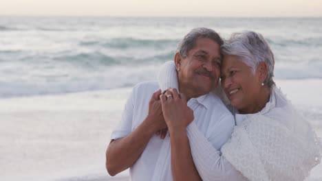 Happy-hispanic-just-married-senior-couple-embracing-on-beach-at-sunset