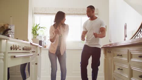 Glückliches-Gemischtrassiges-Paar,-Das-Zusammen-Tanzt-Und-Spaß-In-Der-Küche-Hat
