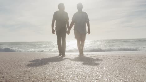 Latin-hispanic-couple-holding-hands,-walking-on-beach-at-sunset