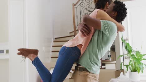 Happy-biracial-couple-hugging-with-joy-in-new-house