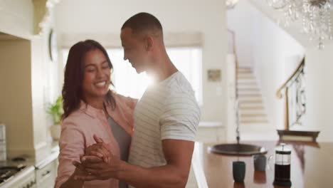 Happy-biracial-couple-dancing-together-in-kitchen