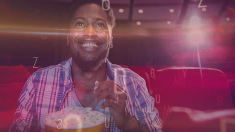 Animation-of-letters-over-smiling-african-american-man-eating-popcorn-in-cinema