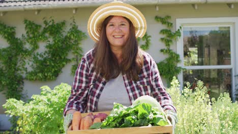 Portrait-of-happy-caucasian-woman-holding-vegetables-and-smiling-in-garden