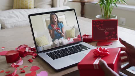 Fröhliche-Afroamerikanische-Frau,-Die-Ein-Geschenk-öffnet-Und-Einen-Videoanruf-Zum-Valentinstag-Auf-Dem-Laptop-Tätigt