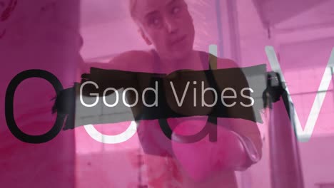 Animation-of-good-vibes-text-over-caucasian-female-boxer-at-gym-punching