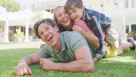 Portrait-of-happy-caucasian-couple-with-son-lying-in-garden