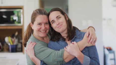 Portrait-of-caucasian-lesbian-couple-looking-at-camera,-embracing