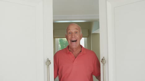 Portrait-of-smiling-senior-caucasian-man-looking-at-camera-and-opening-door
