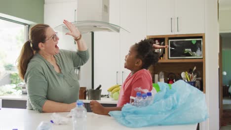 Happy-caucasian-woman-and-her-african-american-daughter-sorting-waste-together