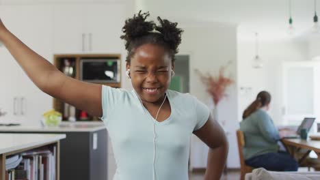 Glückliches-Afroamerikanisches-Mädchen,-Das-Kopfhörer-Trägt-Und-Im-Wohnzimmer-Tanzt