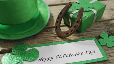 Happy-st-patricks-day-text-with-shamrocks-and-green-hat-with-copy-space-on-wooden-table