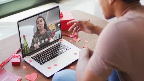 Happy-caucasian-woman-with-champagne-making-valentine's-day-video-call-on-laptop