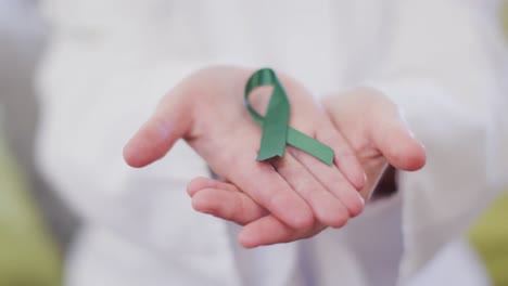 Close-up-of-happy-caucasian-female-doctor-holding-green-awareness-ribbon