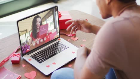 Happy-biracial-woman-with-vitiligo-reading-valentine-card-on-valentine's-day-video-call-on-laptop