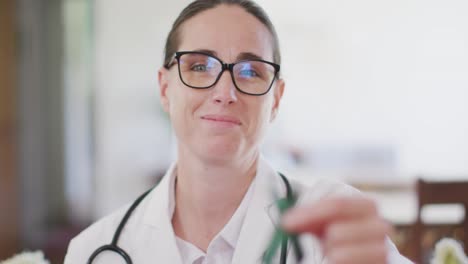 Portrait-of-happy-caucasian-female-doctor-holding-green-awareness-ribbon