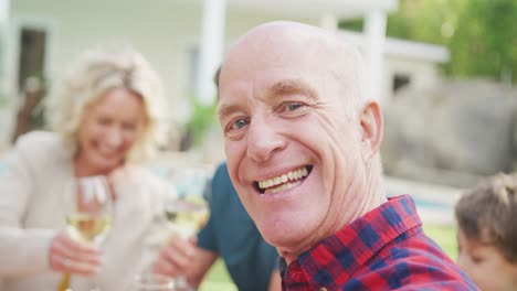 Portrait-of-happy-senior-caucasian-man-having-breakfast-with-family-in-garden