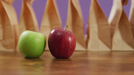 Animation-of-paper-lunch-bags-an-fruits-on-wooden-table