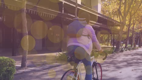 Gelbe-Lichtpunkte-Schweben-Gegen-Eine-Frau,-Die-Auf-Der-Straße-Fahrrad-Fährt
