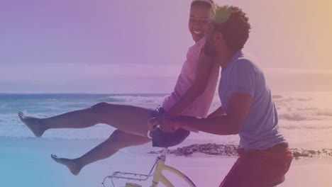 Lichtflecken-Gegen-Afroamerikanisches-Junges-Paar,-Das-Gemeinsam-Mit-Dem-Fahrrad-Am-Strand-Fährt