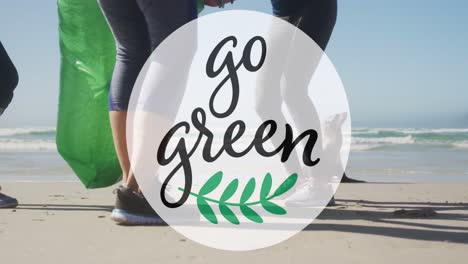 Animation-Von-„Go-Green“-Text-Und--Logo-über-Dem-Unteren-Teil-Einer-Vielfältigen-Gruppe,-Die-Müll-Vom-Strand-Aufsammelt