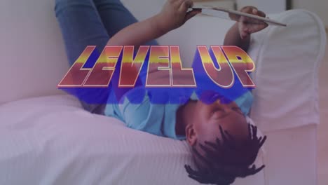 Animation-Von-Level-Up-Text-über-Einem-Afroamerikanischen-Jungen,-Der-Ein-Tablet-Benutzt