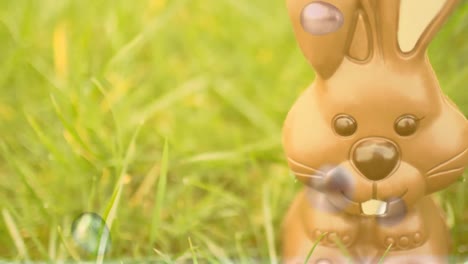 Composite-video-of-easter-egg-falling-and-breaking-against-easter-bunny-on-green-grass