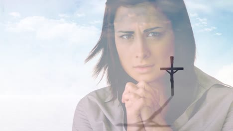 Video-of-crucifix-over-caucasian-woman-praying-on-cloudy-sky