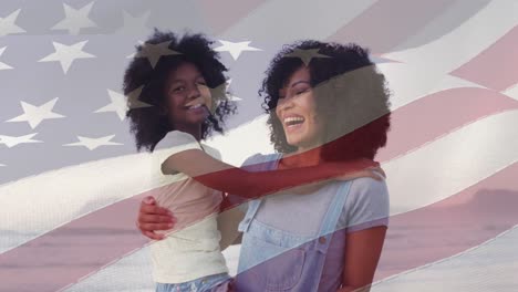 Composite-video-of-american-flag-over-african-american-mother-and-daughter-smiling-at-the-beach