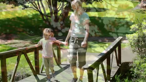 Tall-tress-against-caucasian-mother-and-daughter-holding-hands-walking-together-on-the-bridge