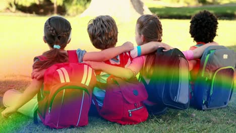 Video-Von-Regenbogennebel-über-Verschiedenen-Kindern,-Die-Auf-Gras-Sitzen