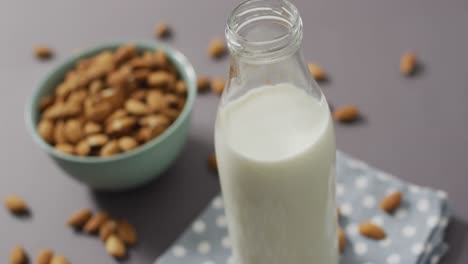 Video-of-fresh-fruit-almonds-in-a-bowl-and-glass-bottle-of-milk-on-grey-background