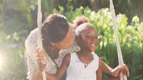Spot-of-light-against-african-american-pushing-her-daughter-on-the-swing-in-the-garden