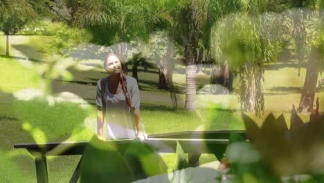 Composite-video-of-close-up-of-leaves-against-caucasian-woman-walking-in-the-garden