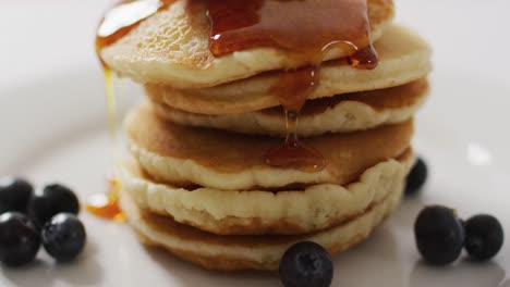 Video-of-pancakes-on-plate-seen-from-above-on-white-background