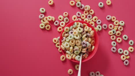 Video-of-colorful-breakfast-cereals-with-bowl-and-spoon-on-pink-background