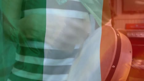 Animation-of-flag-of-ireland-over-biracial-man-playing-drum