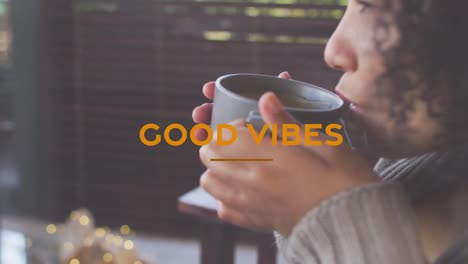 Animation-of-good-vibes-text-with-biracial-woman-drinking-coffee