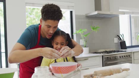 Happy-biracial-father-and-daughter-baking-together-in-kitchen