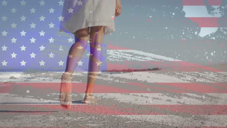 Animation-of-american-flag-over-african-american-woman-walking-at-beach