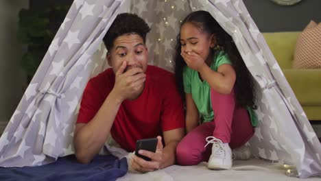Happy-biracial-father-and-daughter-using-smartphone-together